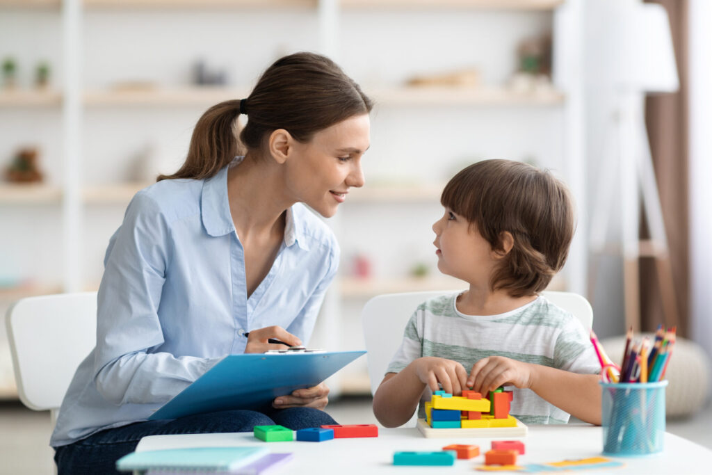 professional woman psychologist exercising with little boy checking readiness school taking